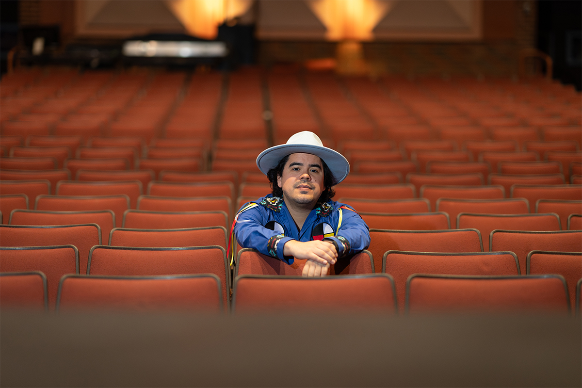 Josh Languedoc sitting in a seat within an empty theatre