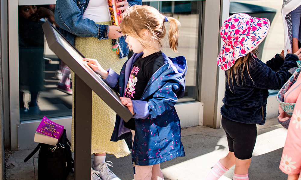 A child interacts with an outdoor sign as part of StoryWalk