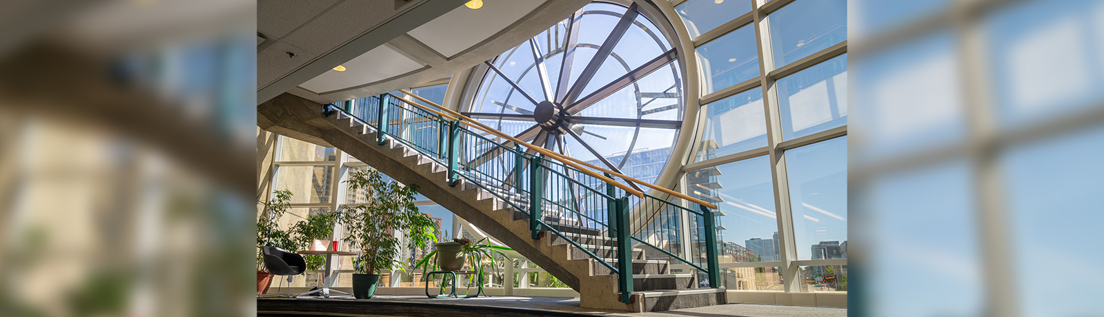 A photograph of an open staircase in front of a glass window with an embedded clock