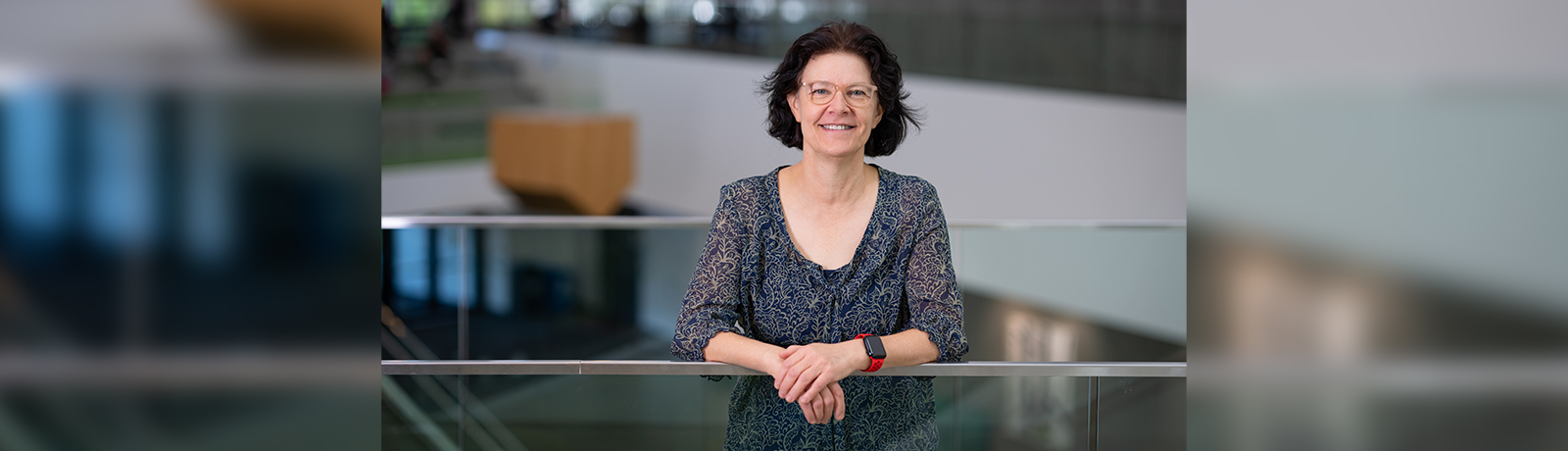 Gail Low stands against a metal railing, smiling at the camera