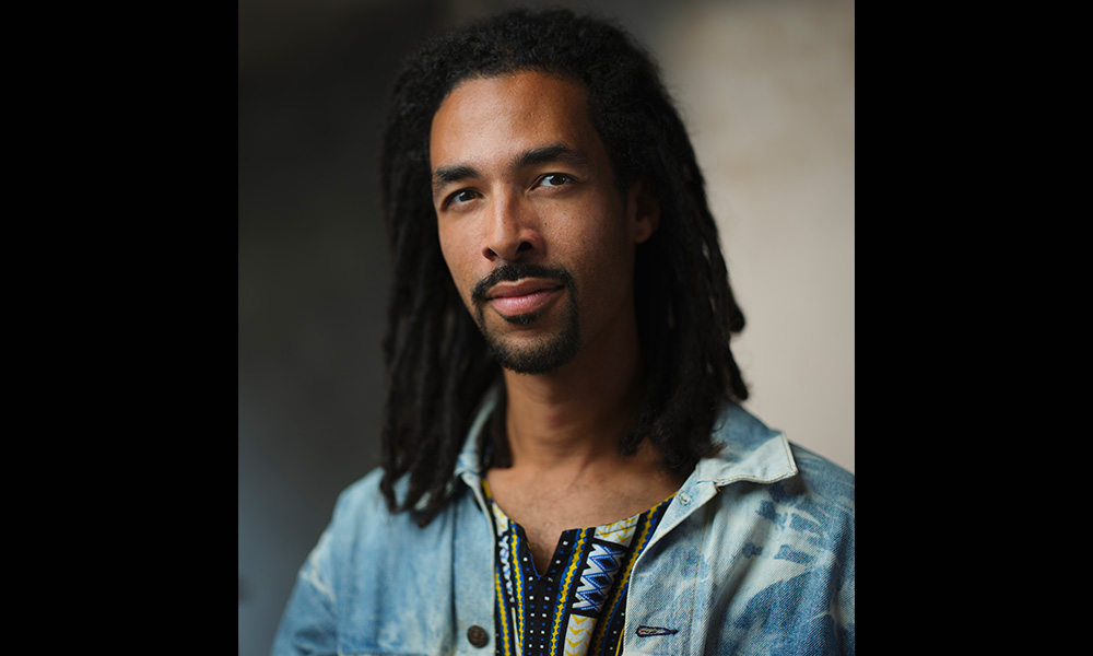 A headshot of a man with dreadlocks.