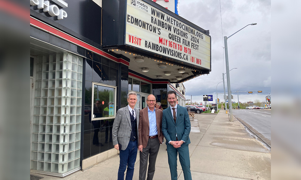 Three people stand in front of the marquee at the Garneau Theatre.