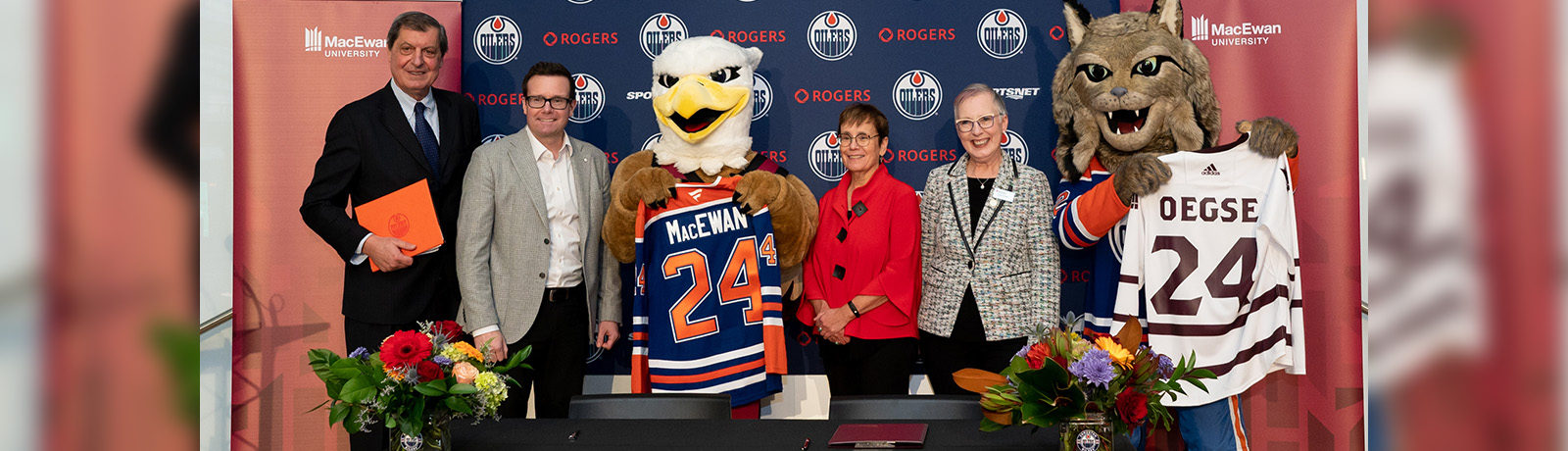 Reps from both the Oilers Entertainment Group and MacEwan stand together with their mascots to celebrate the signing of the memorandum of understanding.