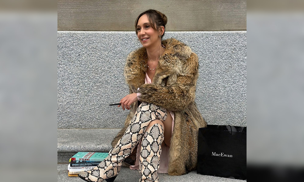 Erika Reitz sits on a stone staircase, wearing a fur coat.