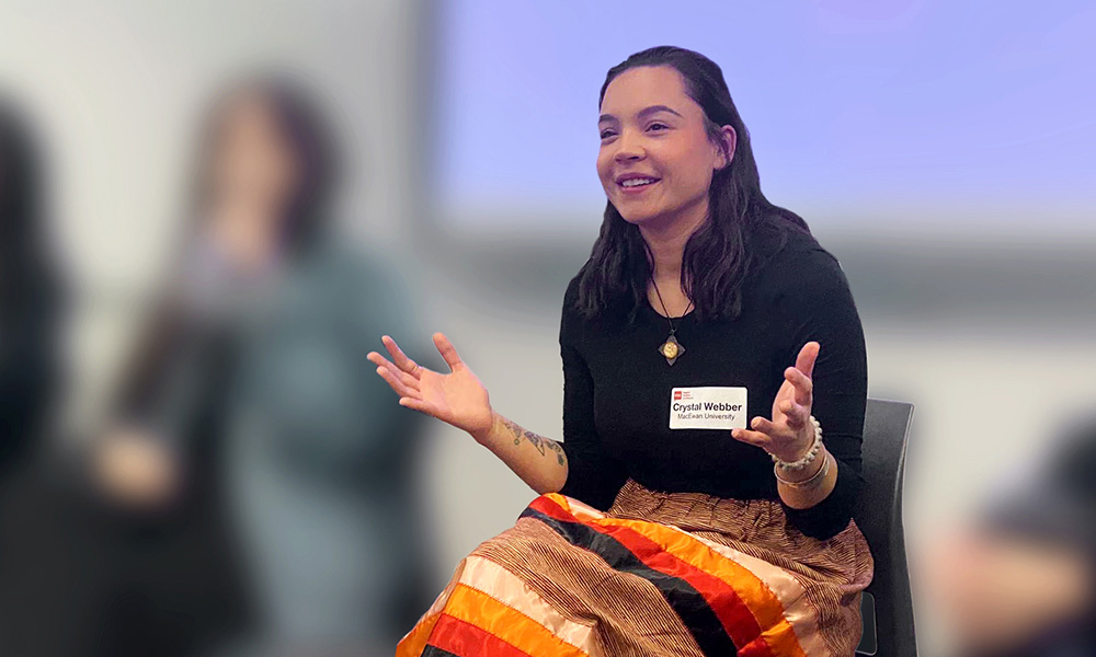 Crystal Webber wears a ribbon skirt and speaks on a panel.