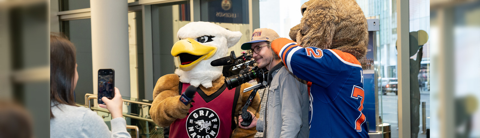 MacEwan and Oilers mascots "assist" a reporter at the event