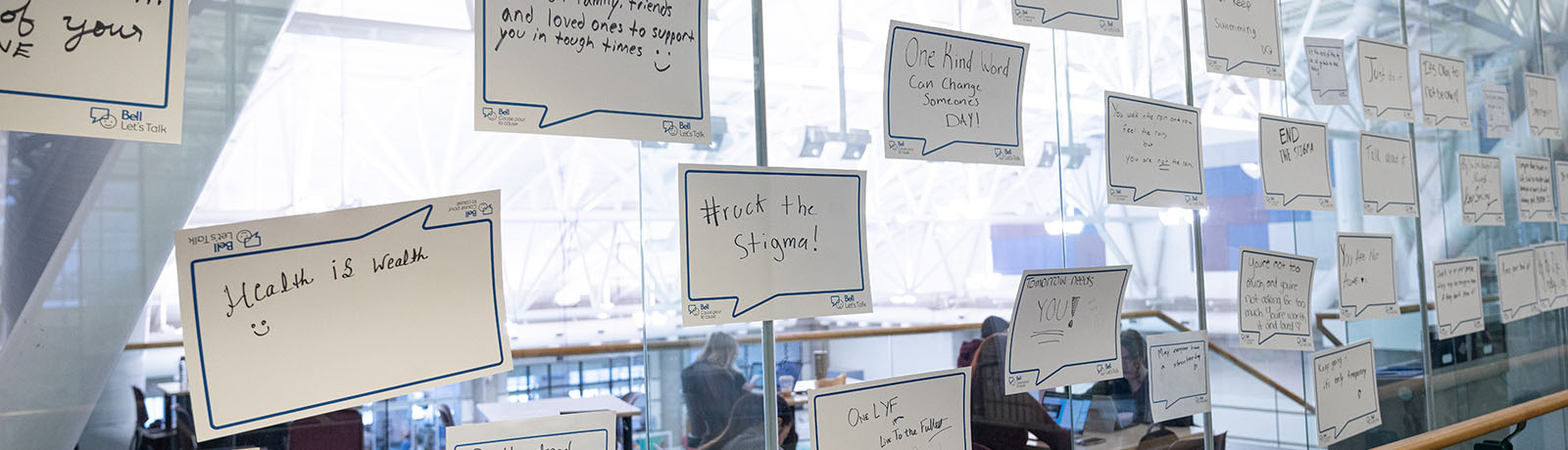 Sheets of paper with positive messages about mental health taped to the glass overlooking the gymnasium