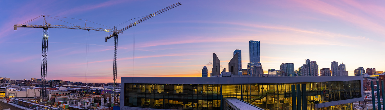 Sunrise cityscape with cranes and buildings in a panoramic shot