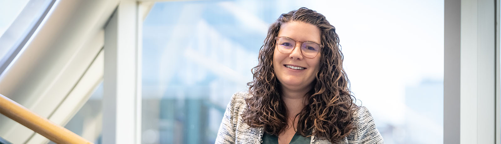 Dr. Kaitlyn Towle stands on the stairs near MacEwan's clock tower