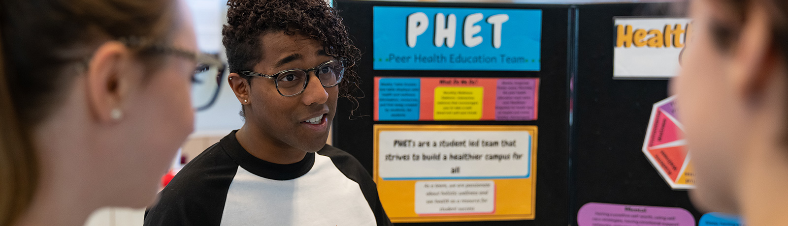 student standing in front of PHET presentation