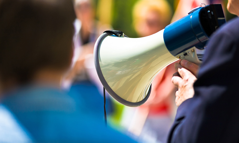 A person in a crowd uses a megaphone